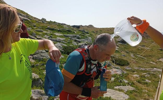 Imagen principal - Los voluntarios y colaboradores de la prueba tuvieron que hidratar y atender a los cientos de participantes asfixiados por el calor. Abajo, el podio masculino del maratón, con el vencedor Borja Fernández, en el centro.