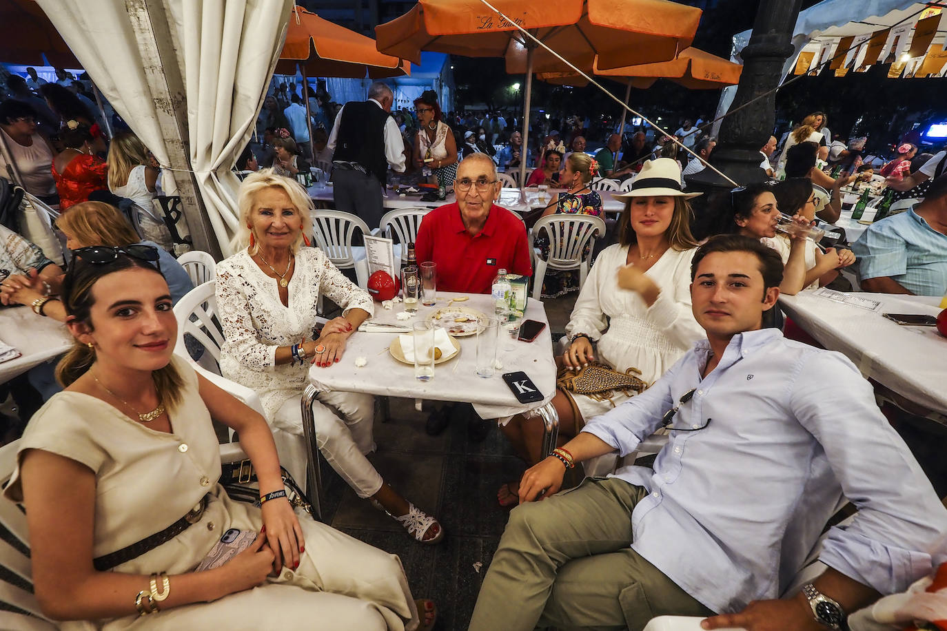 Una familia disfruta de la noche con una tapa en la Hermandad del Rocío. 