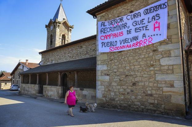 Toñi Gutiérrez, vecina de Herrera de Ibio, pasea ante la pancarta que alguien colgó de madrugada en la iglesia. 