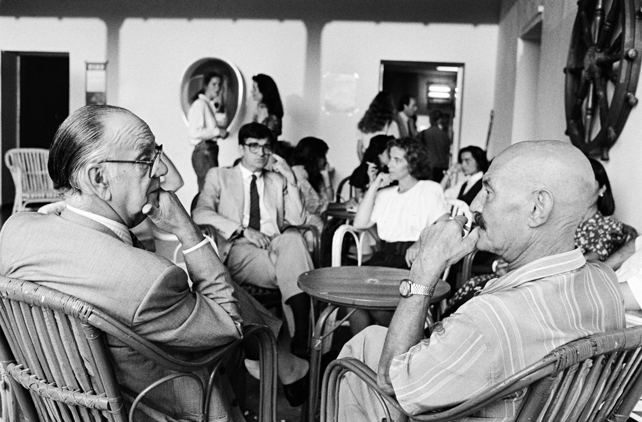 Camilo José Cela y José Hierro, conversando en las Caballerizas, y al fondo, el rector Ernest Lluch, en 1989. 