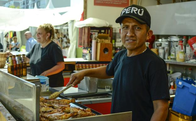Un empleado del puesto peruano cocina carne para sus clientes. 
