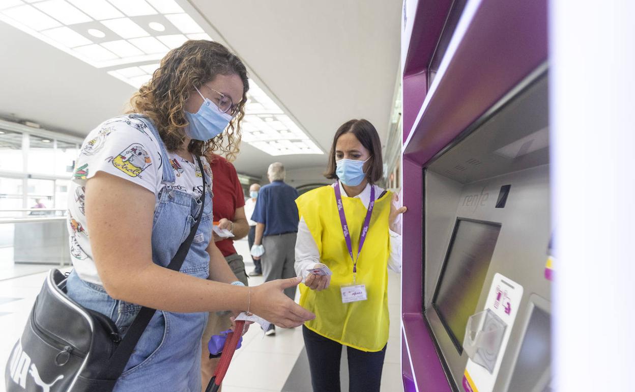 Una empleada de Renfe ayuda a una usuaria en el primer día del abono gratuito. 