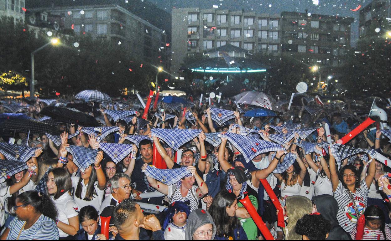 A pesar de la inoportuna lluvia, los vecinos alzaron los pañuelos marineros para cantar a pleno pulmón el himno de Santoña.