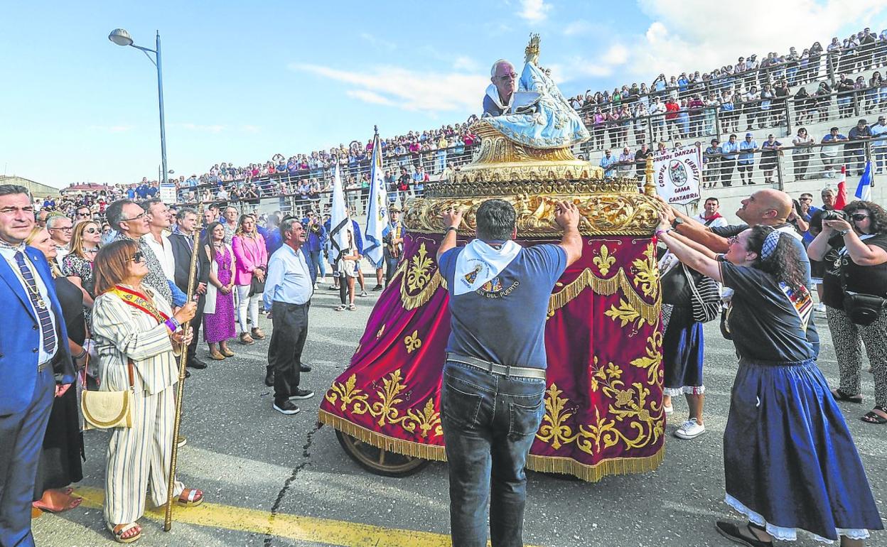 La Virgen del Puerto llega al muelle de Santoña y proceden a bajarla de la carroza para embarcarla ante la mirada de cientos de vecinos y de las autoridades. 