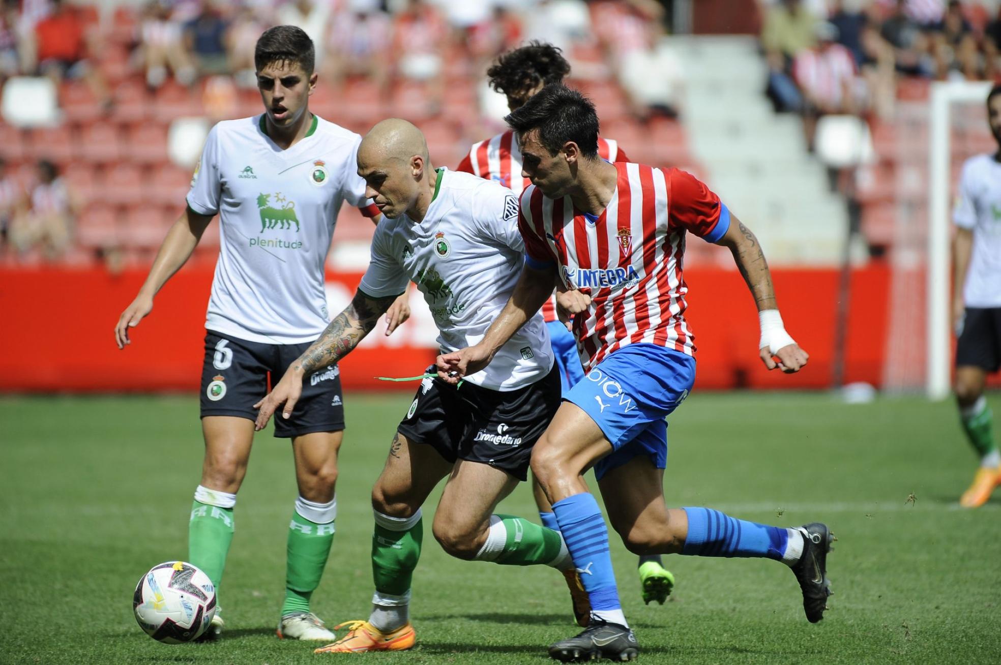 Jorge Pombo conduce la pelota en presencia de Íñigo Sainz-Maza y perseguido por dos rivales en el partido de este domingo en El Molinón. 