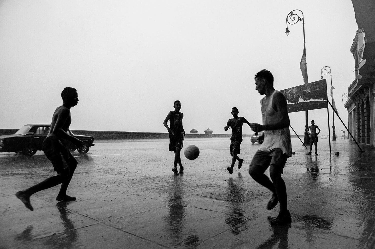 La imagen de Moník, de niños jugando fútbol pick-up en las calles mojadas del Malecón de La Habana.