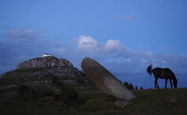 Imagen del menhir con la ermita de las nieves al fondo