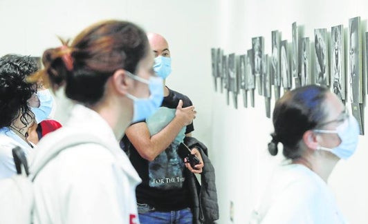 Un grupo observa la muestra fotográfica 'Más allá del dolor' que se puede visitar en la sala de exposiciones de Valdecilla.