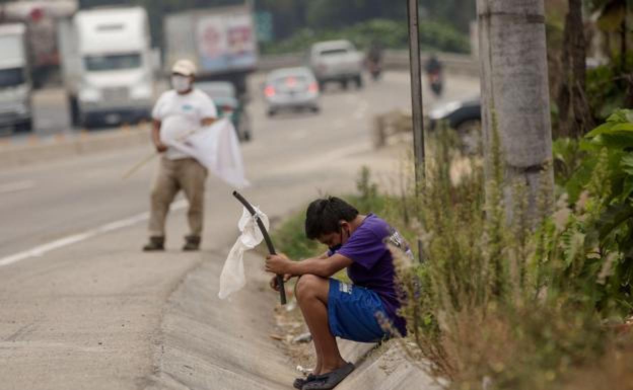 Un niño ondea una bandera blanca en la carretera pidiendo ayuda por hambre debido a la crisis económica en El Tejar (Guatemala). Guatemala. 