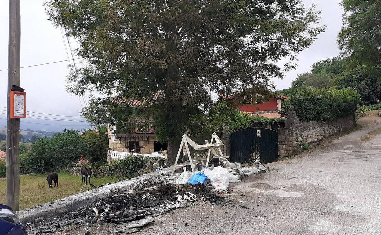 Restos de un contenedor quemado junto a una vivienda. 