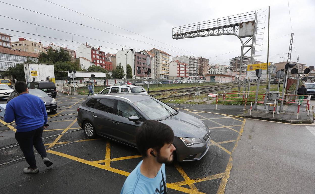 Vehículos y peatones cruzan por las vías de Torrelavega. 