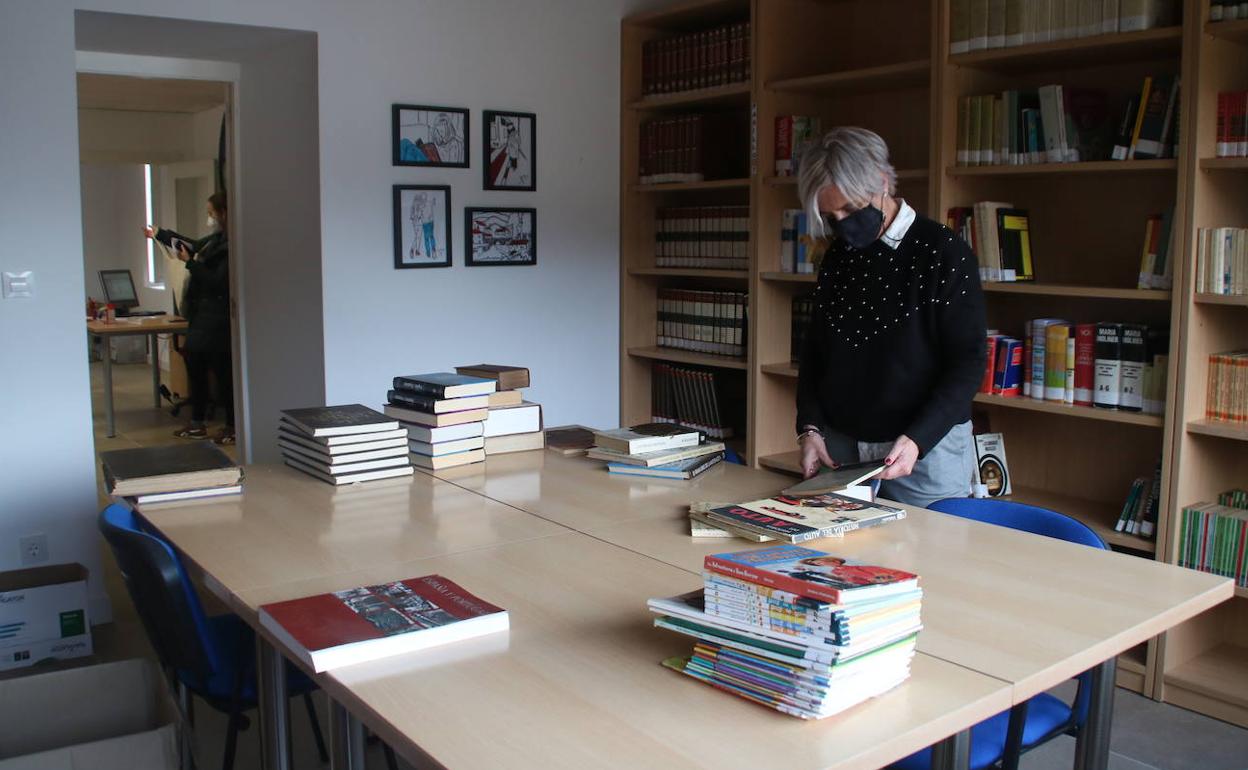 Una de las trabajadoras ordena los fondos bibliográficos de la biblioteca de La Cavada 