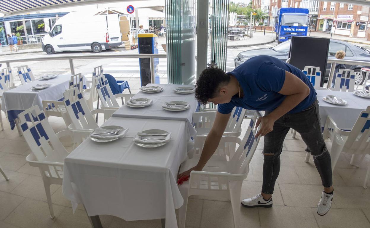 Un camarero prepara la terraza de un establecimiento hostelero en un restaurante de Cantabria.