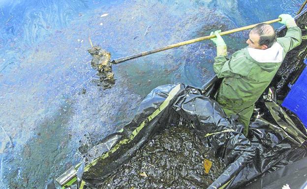 Un marinero recoge chapapote al norte de San Vicente de la Barquera.