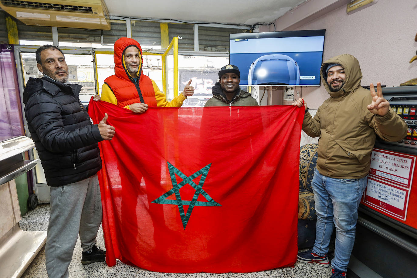 De izquierda a derecha, Ibrahim, Jamal, Alfa y Mohammed sostienen la bandera de Marruecos en el bar 'La Clave', en Torrelavega. 