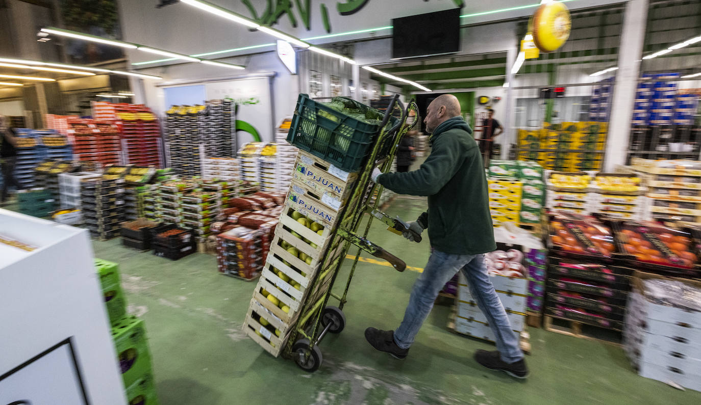 Un mayorista carga con manzanas por el pasillo principal del pabellón de frutas, hortalizas y patatas de Mercasantander.