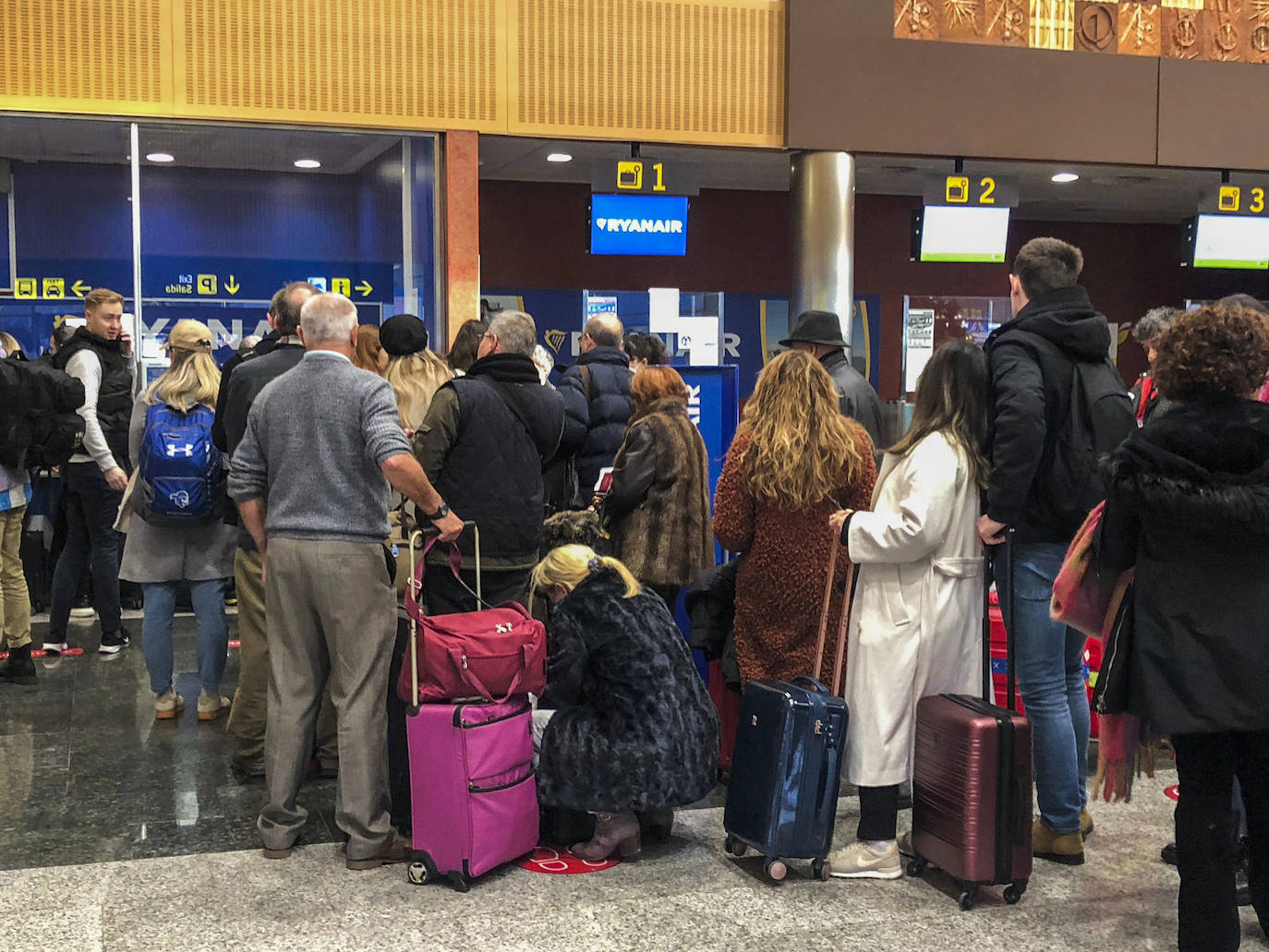 Decenas de pasajeros hacen cola frente a los puestos de Ryanair, tras ser desviados sus vueles este lunes por la mañana.