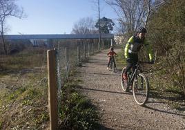 Un padre y su hijo transitan en bicicleta por la zona en la que se construirá la rampa.