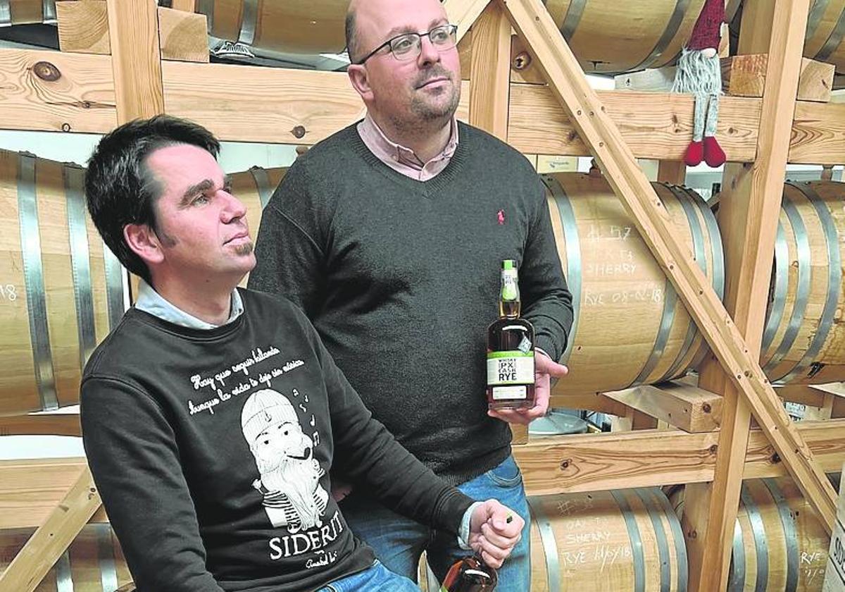 David Martínez y Rubén Leivas sostienen sendas botellas de whisky.