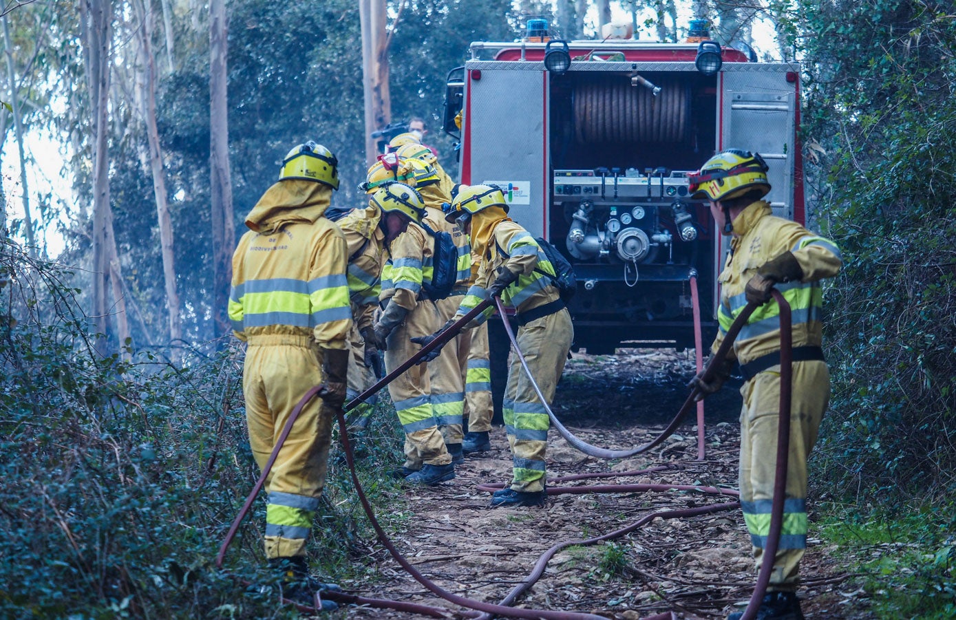 Los bomberos forestales despliegan las mangueras en la cara norte de Peña Cabarga para enfriar el terreno