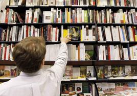 Una empleado coloca un libro en la estantería de una libería.