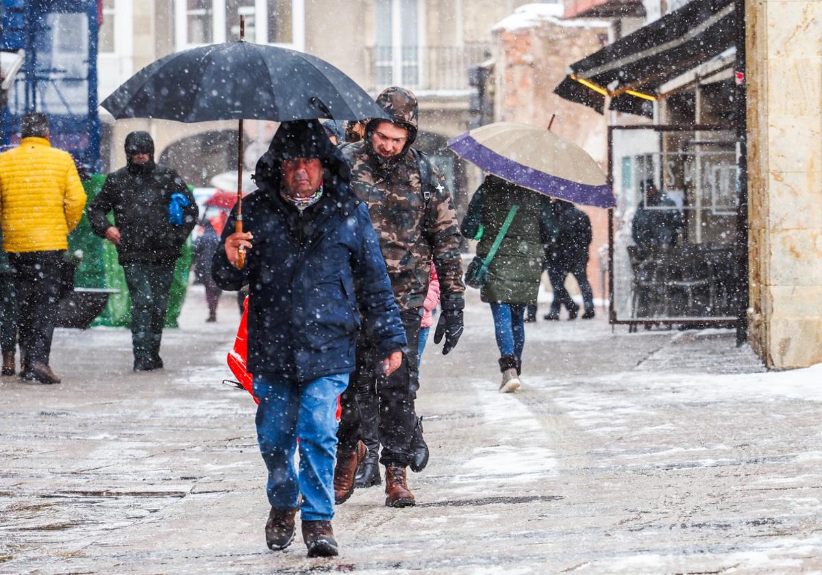 Vecinos de Reinosa caminan ayer por la calle bajo una intensa nevada.