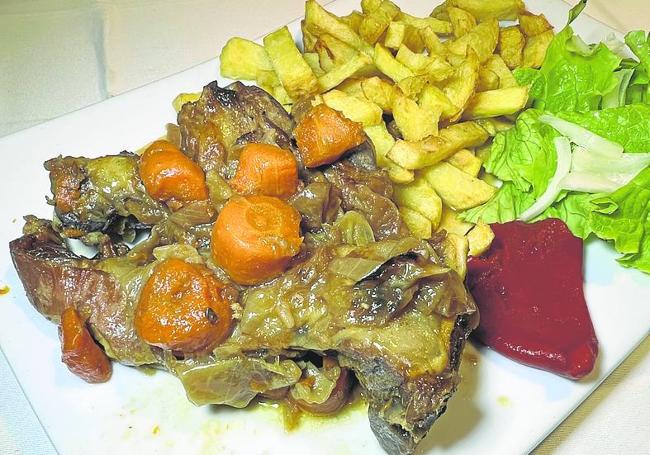 Cabrito de San Roque estofado a fuego lento con patatas, pimientos y ensalada.