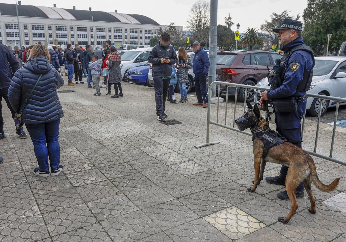 El agente Ismael Abascal, sujetando a su perro, Turko, en los accesos al pabellón Vicente Trueba de Torrelavega.