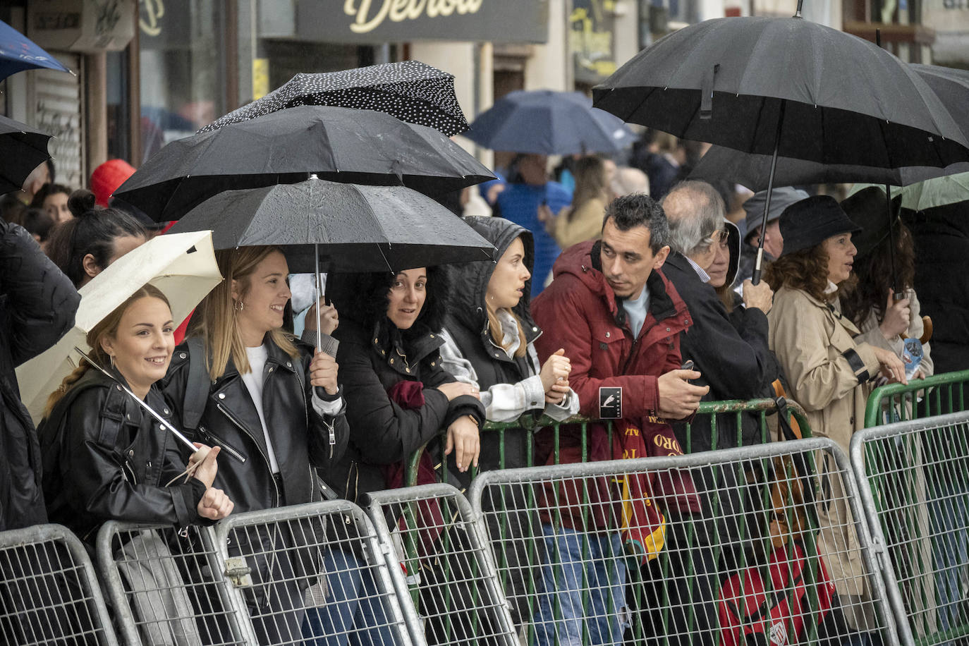 El público se resguarda bajo los paraguas de la fina lluvia que cayó en Laredo.