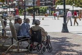 Un grupo de personas mayores conversa en un banco del Bulevar Demetrio Herrero.