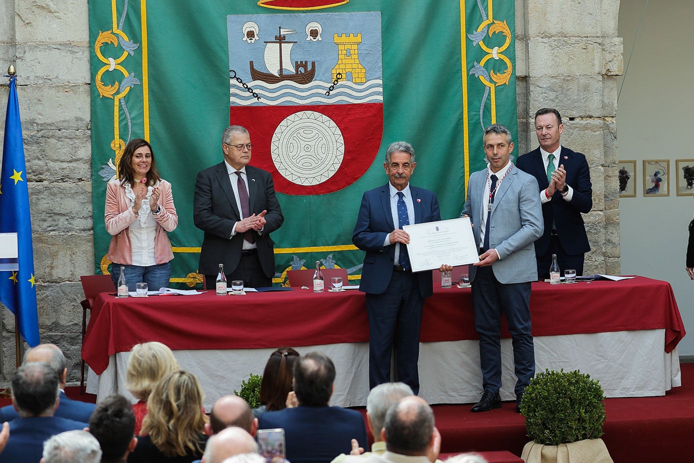 Miguel Ángel Revilla y el ganadero Agapito Fernández sujetan el diploma con el que el Gobierno reconoce el trabajo del profesional