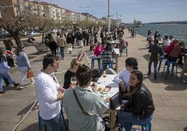 Terraza llena de clientes junto a la bahía de Santander, con el paseo marítimo también repleto de paseantes.