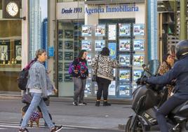 Dos mujeres contemplan la oferta de viviendas que ofrece en su escaparate una inmobiliaria del centro de Santander.