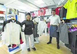 Elena Galdós, empleada, y Óscar Ojea, en la tienda de La Albericia, muestran algunas de las chaquetillas. Elena viste chaquetilla y gorro negros, pantalón estampado y zapatillas con máximo nivel de agarre.