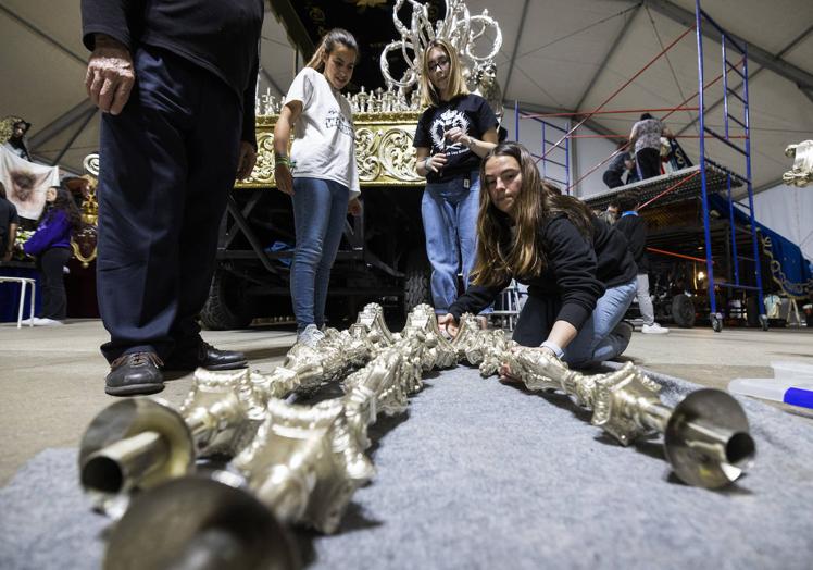 Imagen principal - 1. Momento en que introducen los pernos en los 62 candelabros del paso. | 2. Iván y Daniel, con las coronas de la Virgen y del Cristo, listas para colocar. | 3. Dos cofrades destapan al Cristo del Amor al llegar a la carpa.