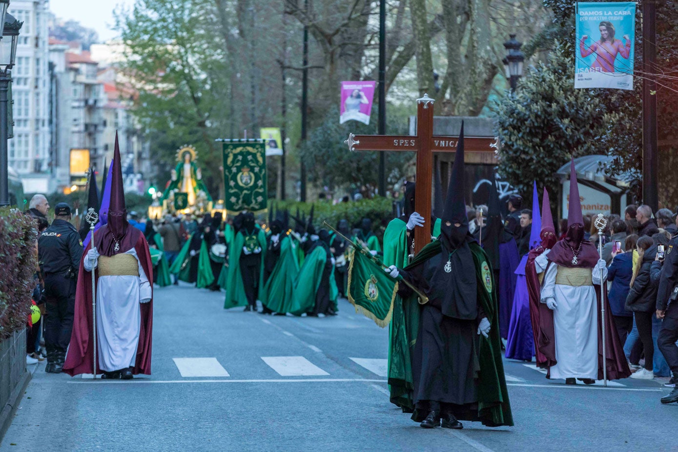 Los nazarenos, con el paso del la Virgen de la Esperanza, al fondo, a su paso por la calle San Fernando.