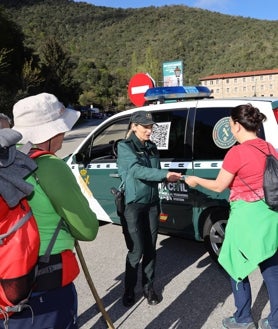 Imagen secundaria 2 - Arriba, un efectivo, fuertemente armado, durante el desarrollo del acto religioso. Abajo, una agente atiende a los peregrinos en las inmediaciones del monasterio