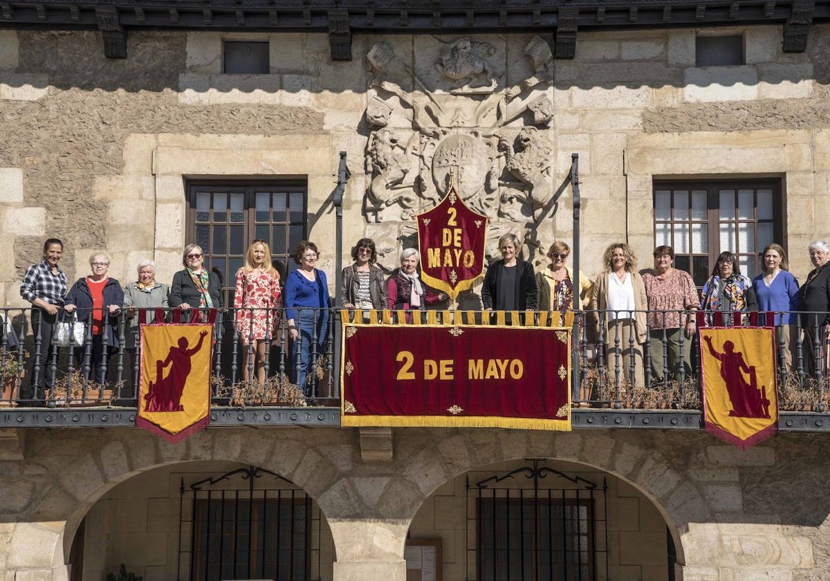 Representantes políticos con participantes y responsables de los talleres en el Ayuntamiento, donde ya están colocados en la fachada los adornos para la celebración de Pedro Velarde.