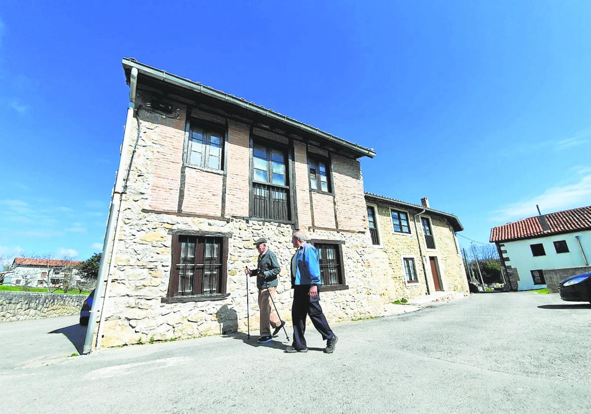 Dos vecinos pasean por uno de los edificios recuperados en Reocín, en La Veguilla.