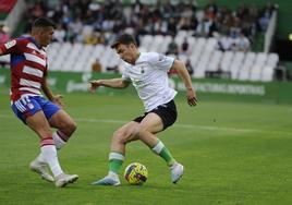 Un jugador verdiblanco trata de driblar a un contrario del Granada.