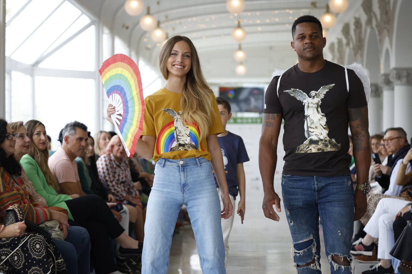 Los modelos María Fernanda Pardo y Gregory Heredia con la camiseta de Pumba Lumba del ángel exterminador que vigila desde 1895 la entrada del cementerio de Comillas. Pardo luce la versión 'pop' con abanico a juego.