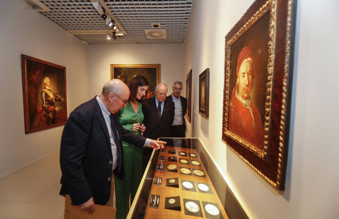 Autoridades y organziadores miran una de las colecciones de monedas incluida en la sección de retratos