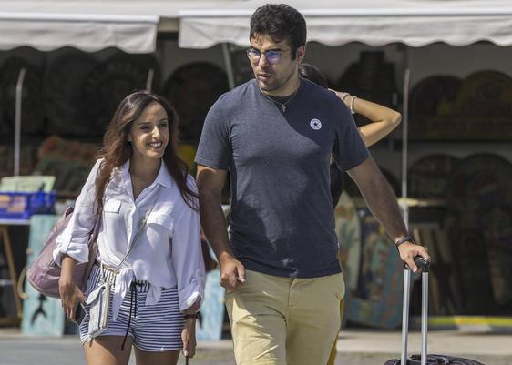 Dos turistas con maletas pasean por el centro de la ciudad.