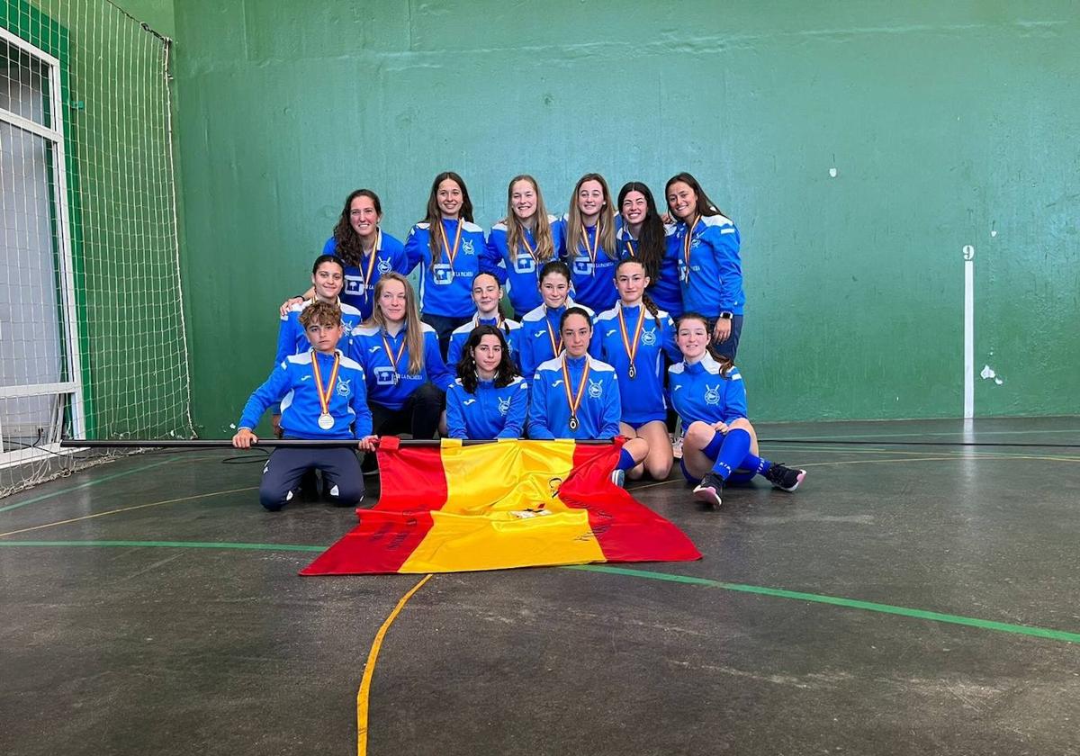 Las tripulaciones absoluta y cadete posan con la bandera y sus medallas.