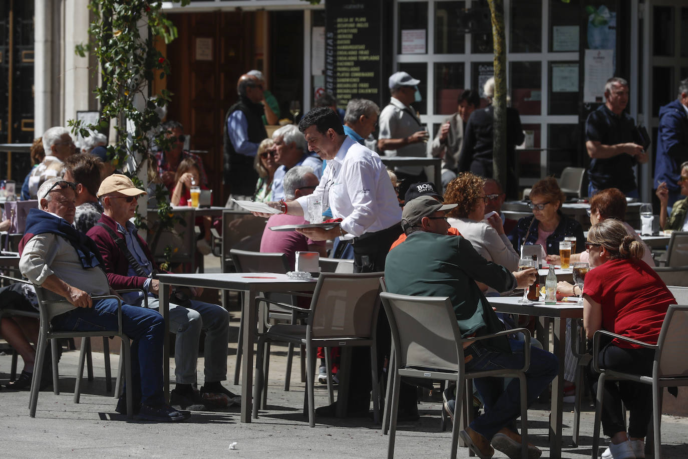 Un camarero sirve en una terraza de Santander la consumición a unos clientes en una mañana soleada de lunes. 