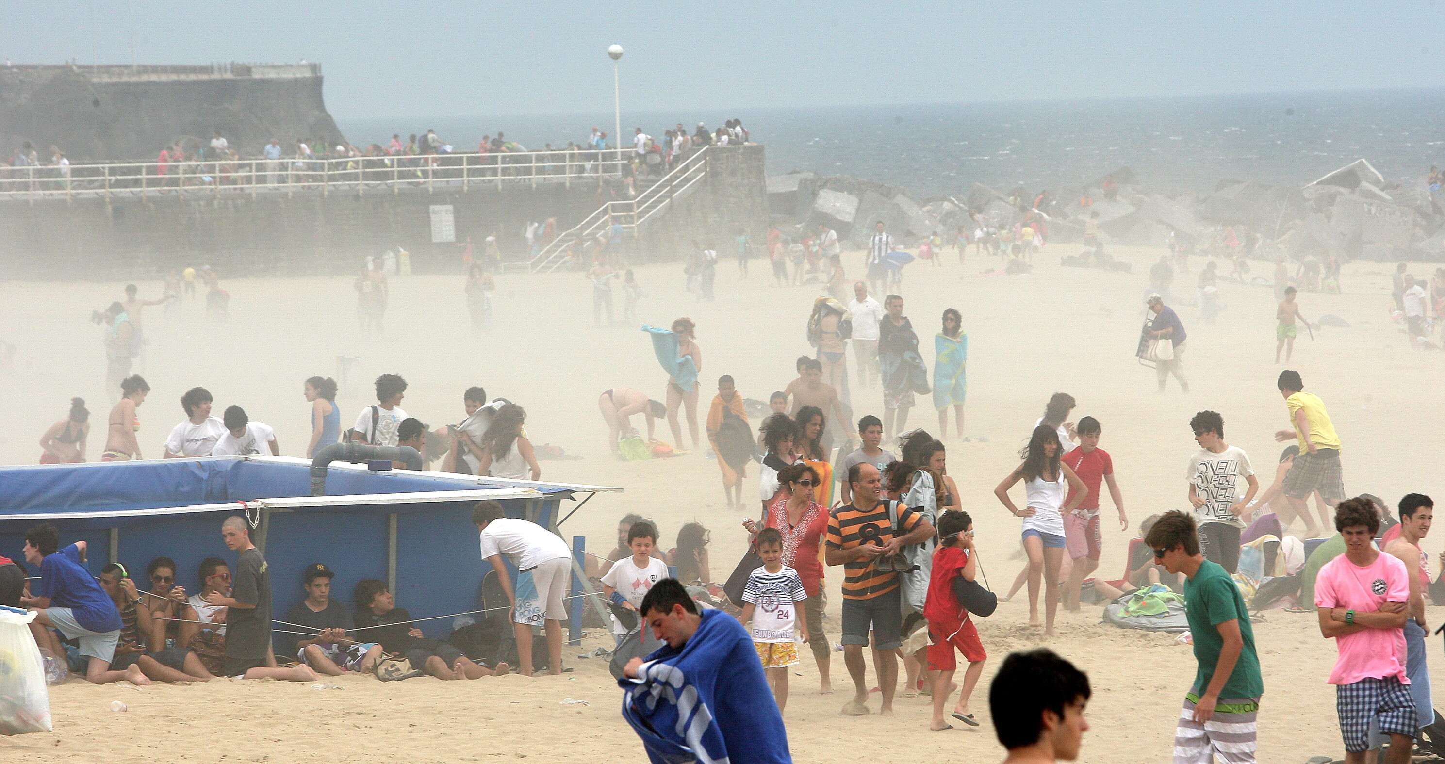 Turistas y vecinos que habían acudido a la playa se refugian del fuerte viento.