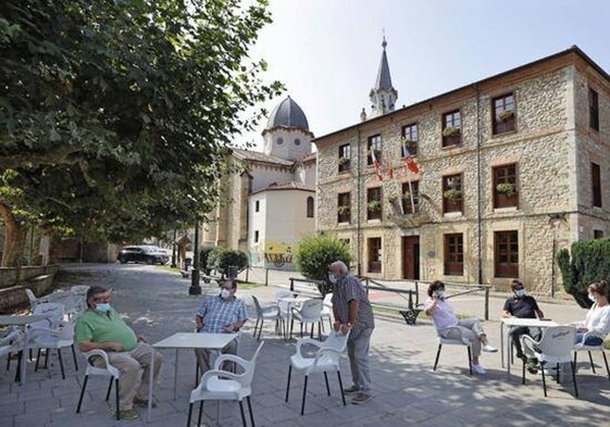 Vecinos en una terraza frente al edificio consistorial del barrio de la Iglesia, en Ruiloba.