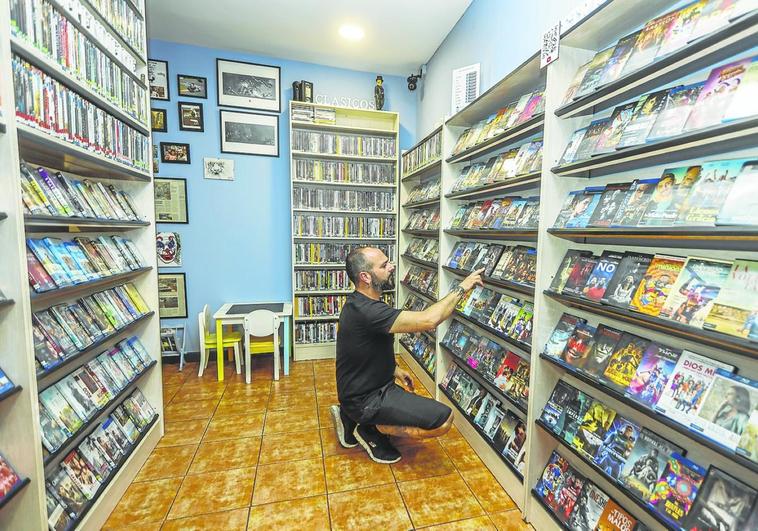 Julián Bárcena coloca las carátulas de las películas en las estanterías.