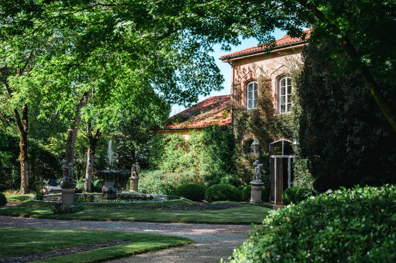 Vista de la casa de invitados, cubierta con una buganvilla 'glabra sanderiana', con la fuente principal del jardín.