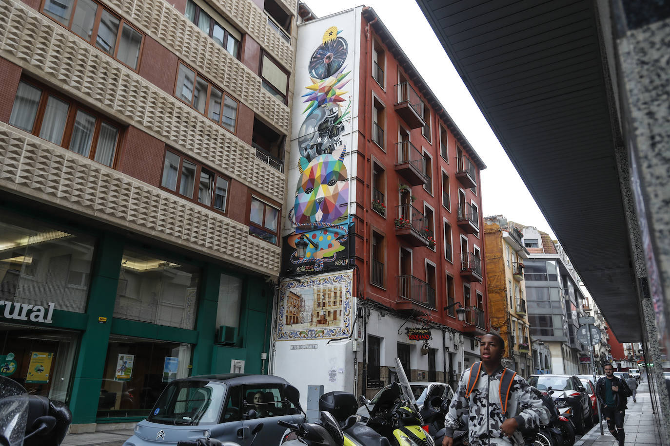 La huella del artista cántabro Okuda llega al Río de la Pila, al inicio de la calle, justo encima de un tradicional mural de azulejos. Okuda ha triunfado a nivel internacional dentro del arte urbano, con obras de gran formato y figuras fragmentadas en formas geométricas y fuerte policromía.